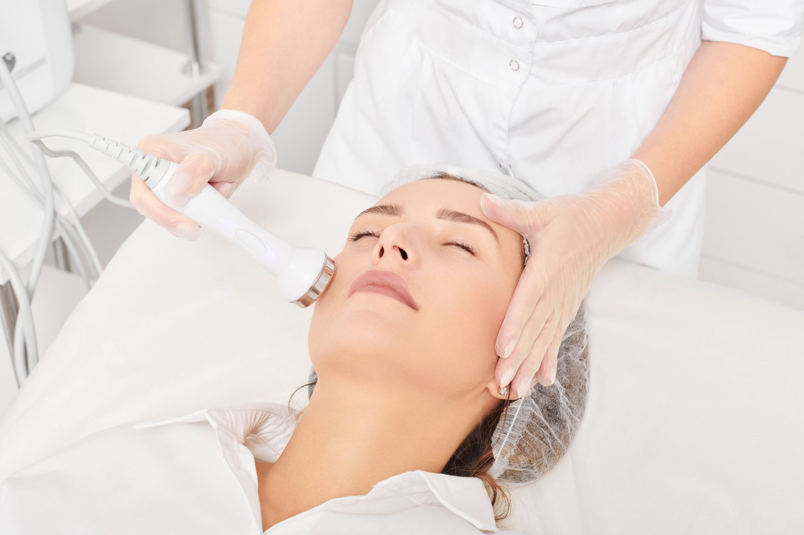 Cosmetologist makes ultrasound skin tightening for rejuvenation woman face using phonophoresis